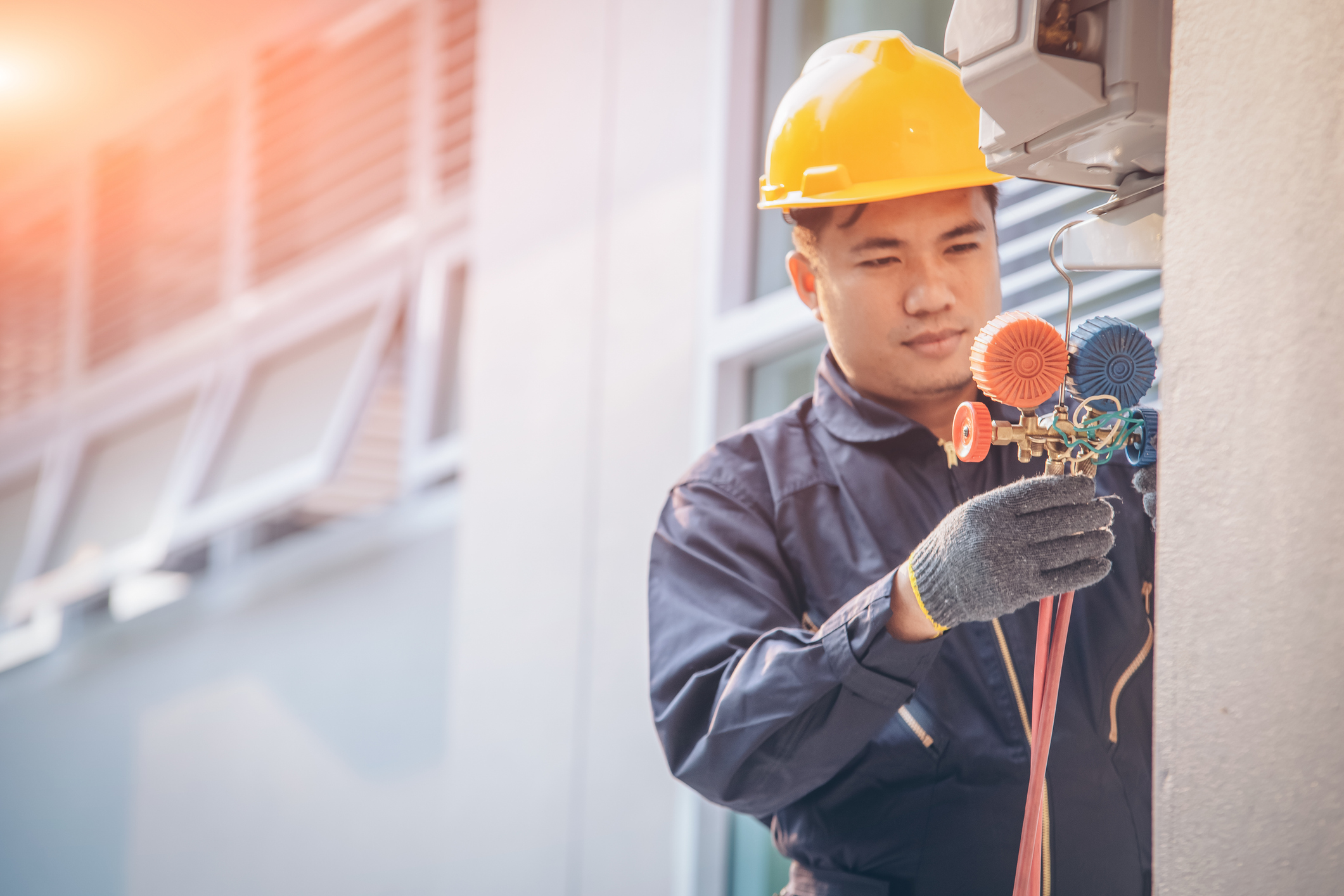 Technician vacuum pump evacuates and checking new air conditioner,Male technician repairing air conditioner outdoors.